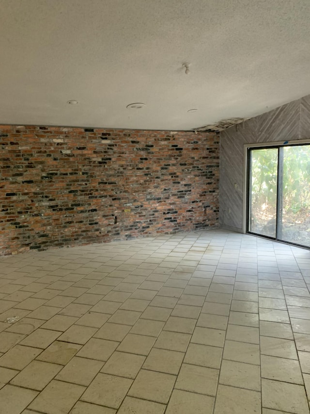 empty room with brick wall and a textured ceiling