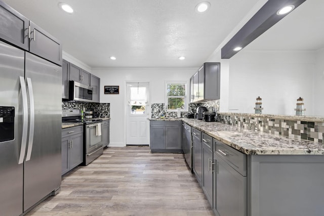 422 49th St, West Palm Beach, FL 33407 - kitchen with appliances with stainless steel finishes, ornamental molding, decorative backsplash, light stone counters, and gray cabinets