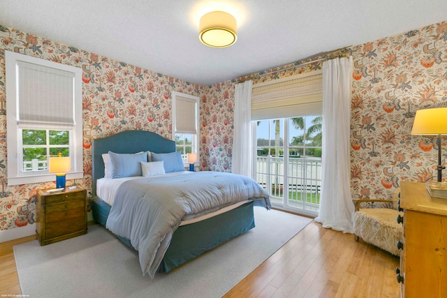 bedroom featuring light hardwood / wood-style floors, access to exterior, and multiple windows