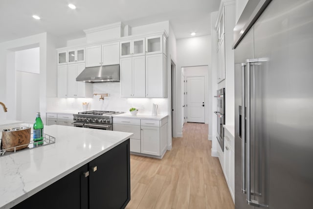 kitchen with white cabinets, high quality appliances, and light wood-type flooring