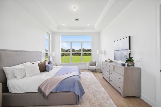 bedroom featuring a tray ceiling and light wood-type flooring