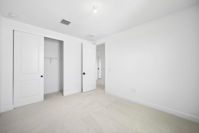 unfurnished bedroom featuring light carpet and a closet