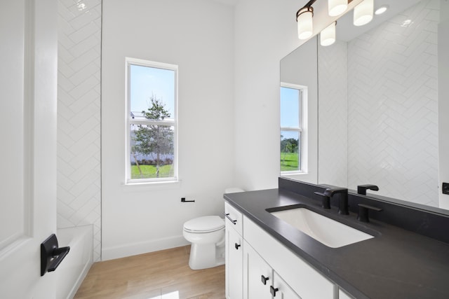 full bathroom with a wealth of natural light, toilet, oversized vanity, and hardwood / wood-style floors