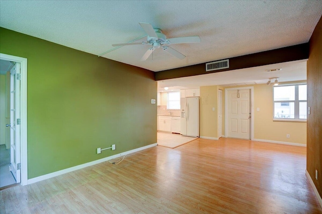 interior space with ceiling fan, light hardwood / wood-style floors, and a textured ceiling