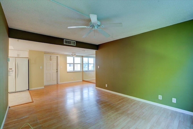 unfurnished bedroom with light wood-type flooring, a textured ceiling, ceiling fan, and white refrigerator with ice dispenser