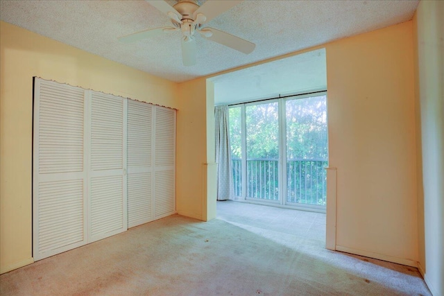 unfurnished bedroom featuring a closet, light colored carpet, ceiling fan, and a textured ceiling