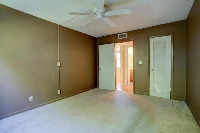 unfurnished bedroom with light carpet, a textured ceiling, ceiling fan, and a closet