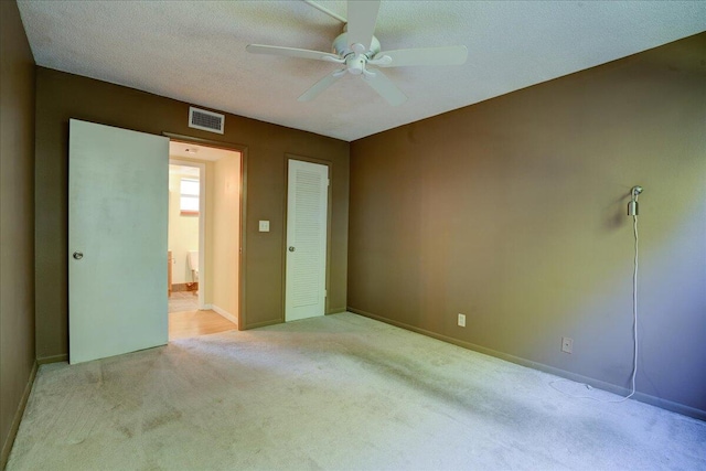 spare room with ceiling fan, light carpet, and a textured ceiling