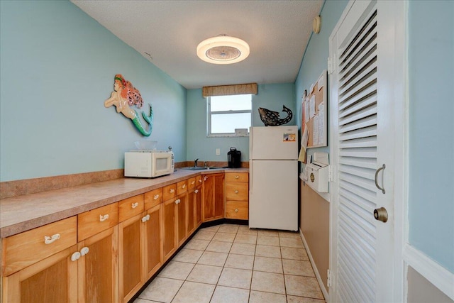 kitchen with light tile patterned floors, white appliances, sink, and a textured ceiling