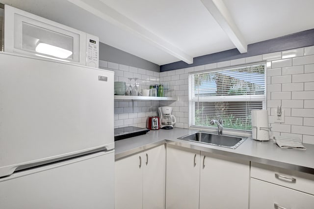 kitchen with white appliances, sink, white cabinets, backsplash, and lofted ceiling with beams