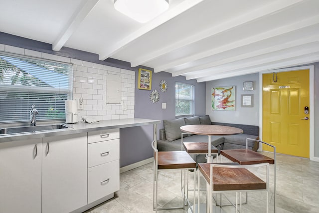 dining area with lofted ceiling with beams, light tile floors, and sink