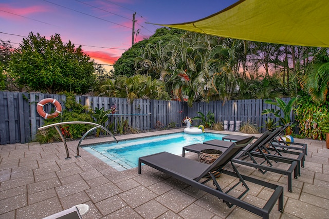 pool at dusk featuring a patio area