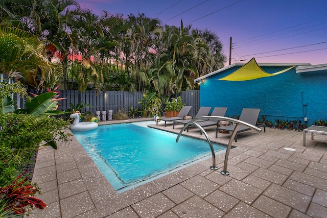 pool at dusk featuring a patio area