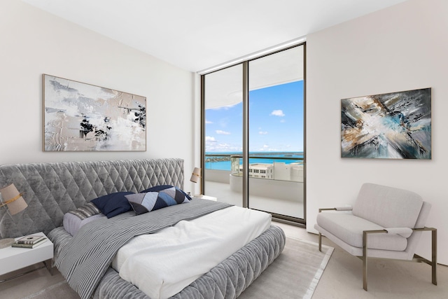 bedroom with a water view, access to exterior, and a wall of windows