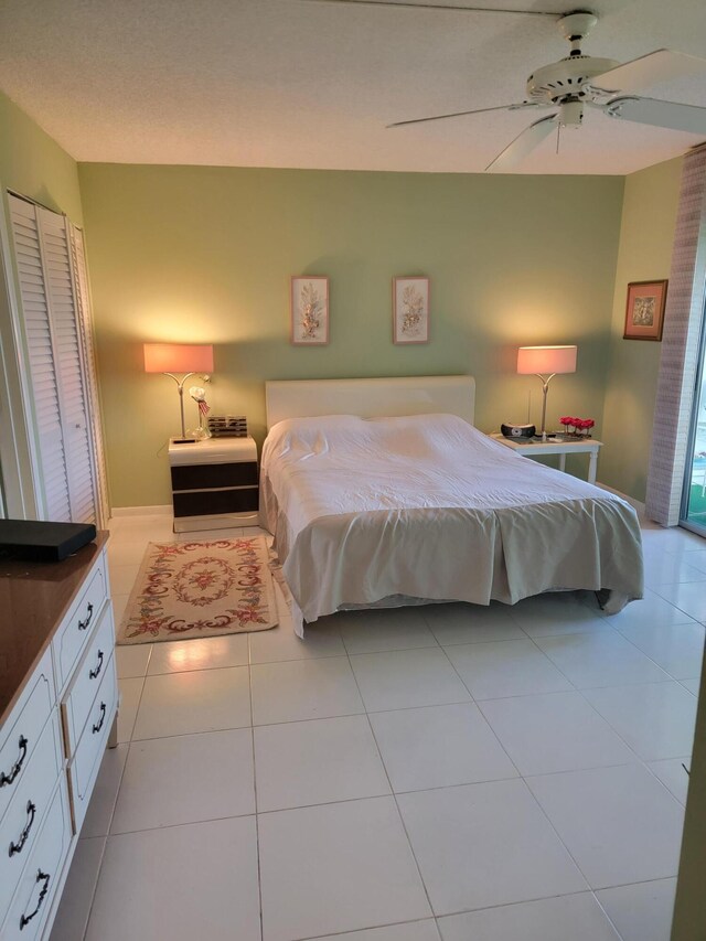 tiled bedroom with ceiling fan, a textured ceiling, and access to exterior