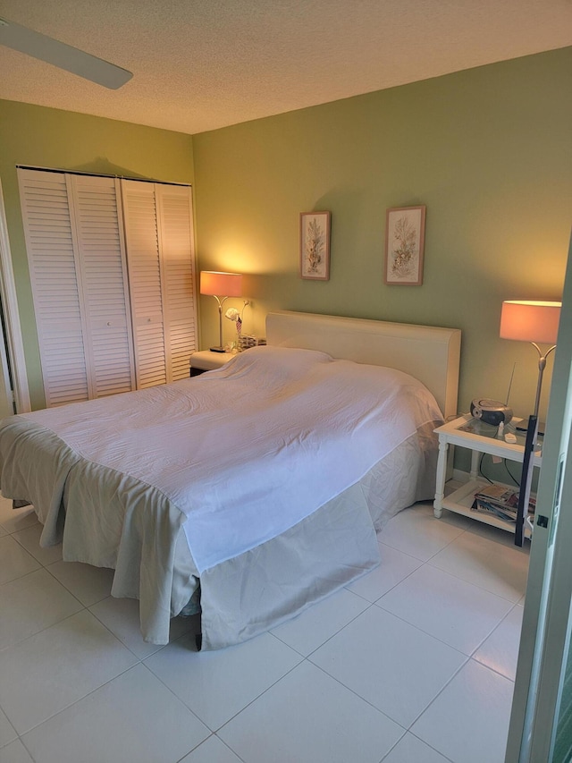 tiled bedroom with a closet and a textured ceiling