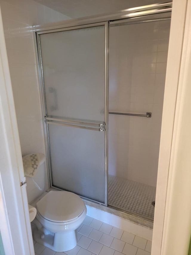 full bath with toilet, a stall shower, and tile patterned floors