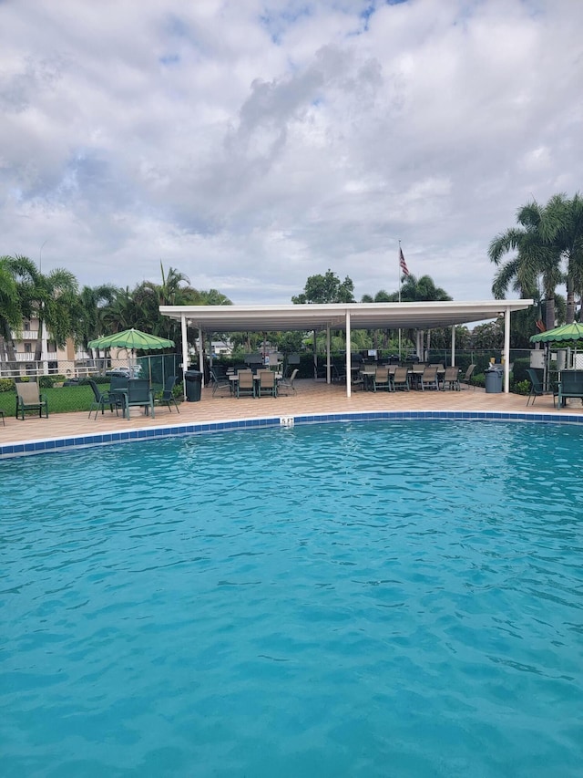 community pool with a patio area and fence