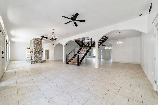 unfurnished living room with light tile floors, ceiling fan with notable chandelier, and a fireplace