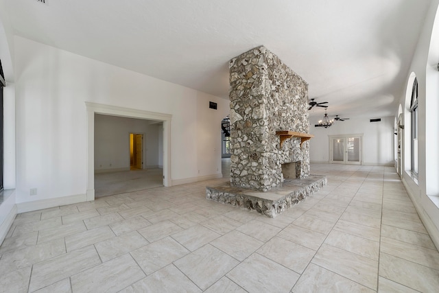 unfurnished living room featuring light tile flooring, a stone fireplace, and ceiling fan