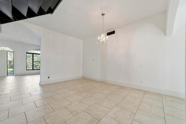 tiled empty room with an inviting chandelier