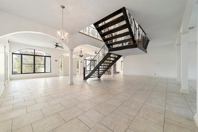 interior space featuring light tile flooring, decorative columns, a high ceiling, and ceiling fan with notable chandelier