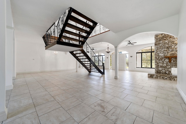 stairs with ceiling fan with notable chandelier, light tile floors, and a towering ceiling