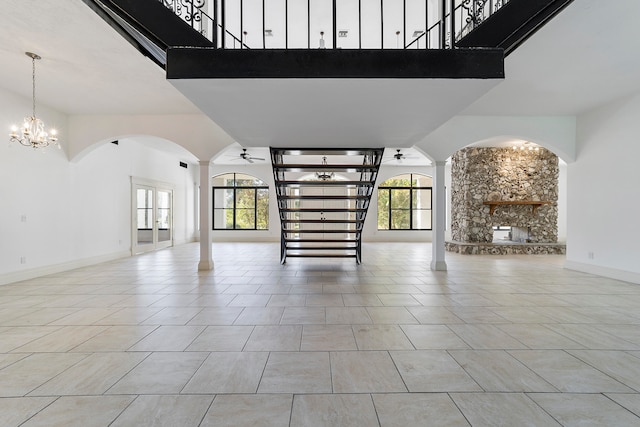 unfurnished living room with a healthy amount of sunlight, light tile flooring, and ceiling fan with notable chandelier