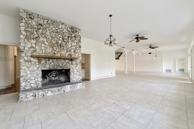 unfurnished living room with a stone fireplace, ceiling fan with notable chandelier, and light tile flooring