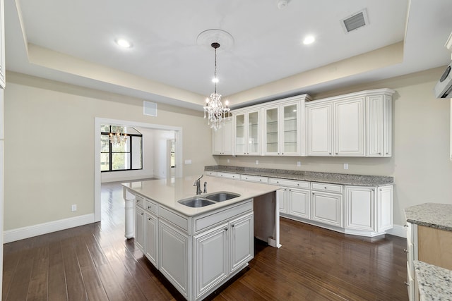 kitchen with dark hardwood / wood-style floors, sink, white cabinets, a chandelier, and a raised ceiling