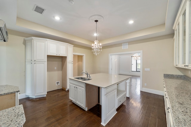 kitchen featuring dark wood-type flooring, a notable chandelier, white cabinetry, and a raised ceiling