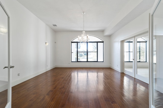 spare room featuring a chandelier, dark hardwood / wood-style floors, and french doors