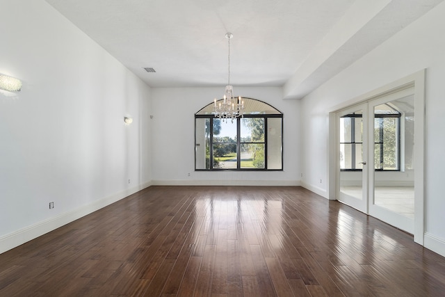 empty room featuring a notable chandelier and dark wood-type flooring