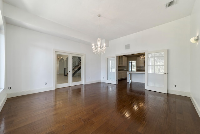 spare room with an inviting chandelier and dark wood-type flooring