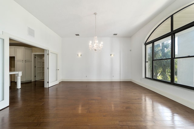 empty room featuring an inviting chandelier and dark wood-type flooring