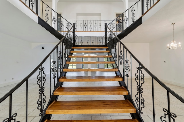 staircase with a chandelier, light tile flooring, and a high ceiling