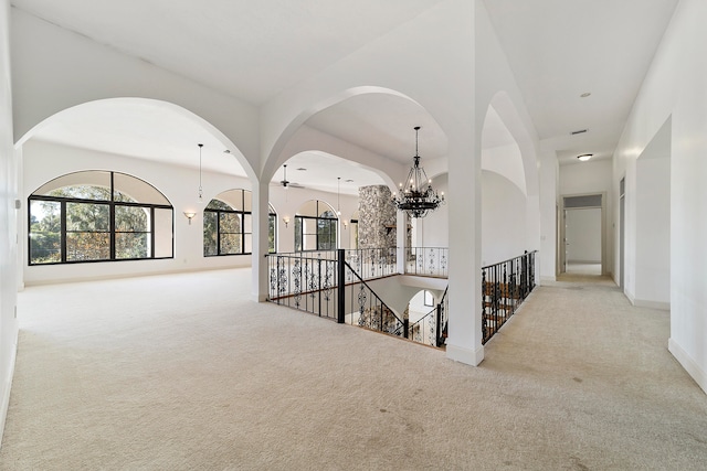 corridor with a notable chandelier and light colored carpet