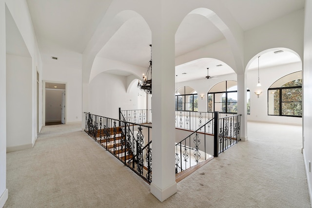 corridor with a notable chandelier and light colored carpet