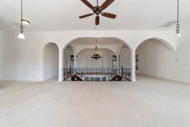 empty room with ceiling fan with notable chandelier and light colored carpet