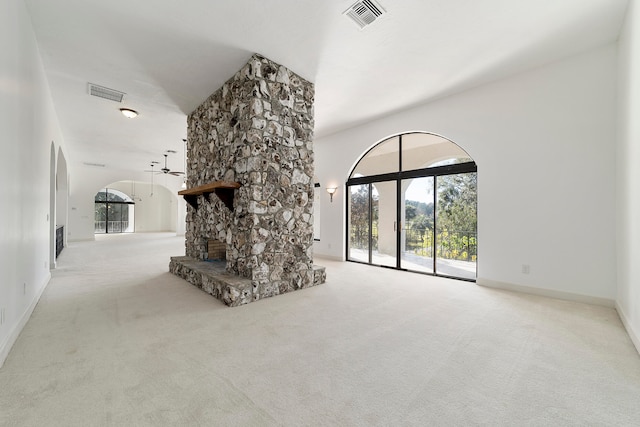 unfurnished living room with light colored carpet and a stone fireplace