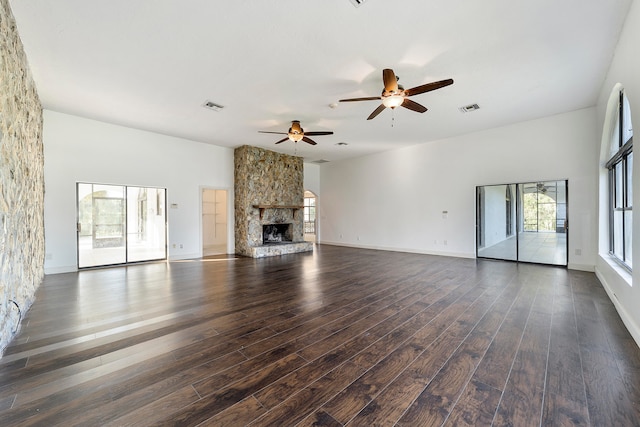 unfurnished living room with a stone fireplace, ceiling fan, and dark hardwood / wood-style flooring