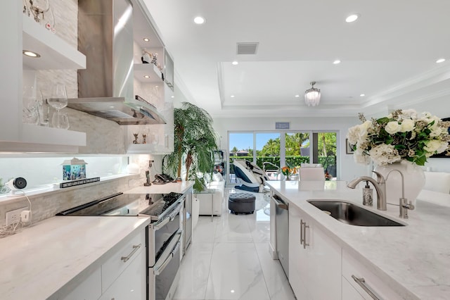 kitchen featuring appliances with stainless steel finishes, white cabinets, wall chimney exhaust hood, and sink