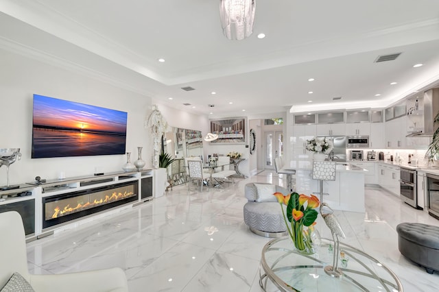 living room with sink, light tile floors, crown molding, a tray ceiling, and an inviting chandelier