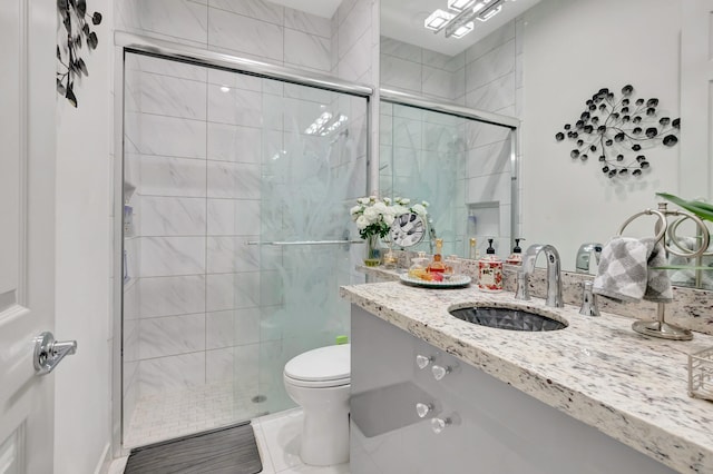 bathroom featuring tile flooring, a shower with shower door, oversized vanity, and toilet