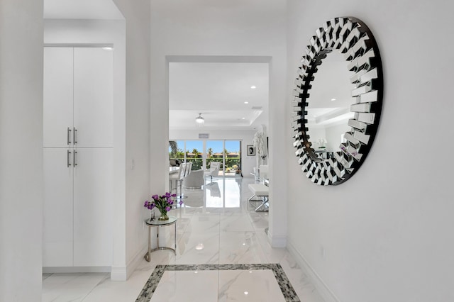 corridor with a tray ceiling and light tile floors