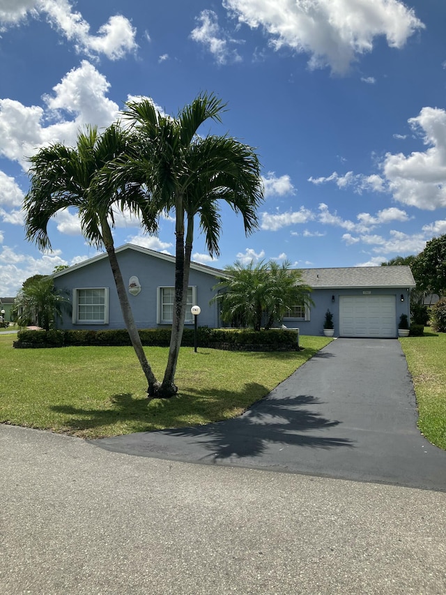 ranch-style house with stucco siding, an attached garage, driveway, and a front lawn