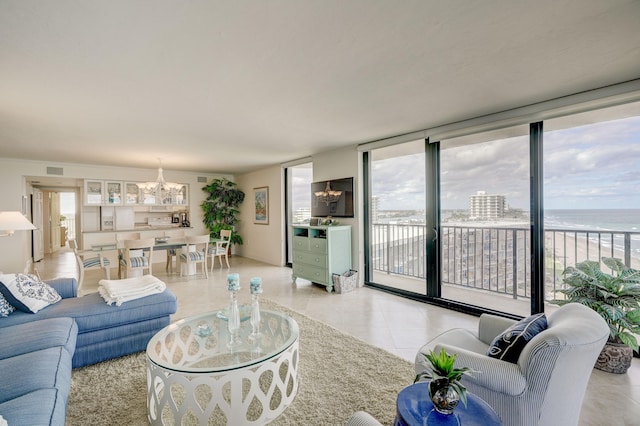 living room with light tile floors, an inviting chandelier, a healthy amount of sunlight, and a water view