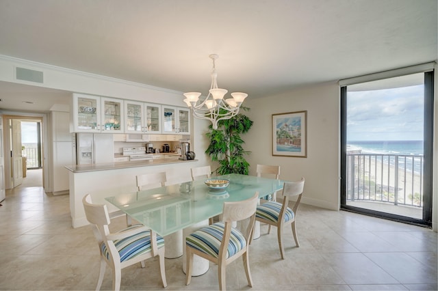 dining space with crown molding, light tile floors, a water view, and a chandelier