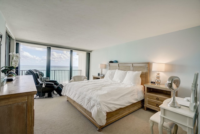 carpeted bedroom with access to outside, floor to ceiling windows, and a water view