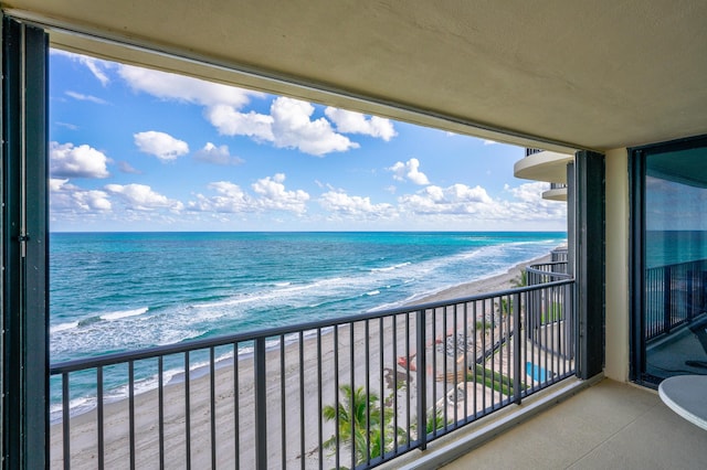 balcony with a water view and a view of the beach